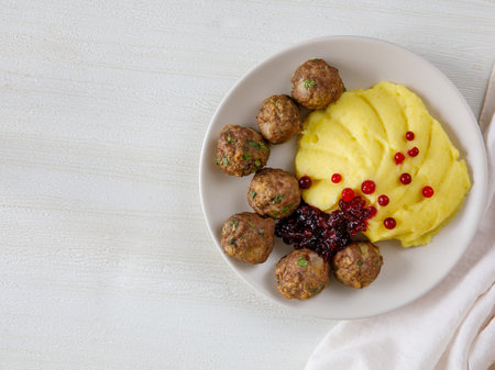 Swedish Kottbullar meatball with mashed boiled potatoes and cowberry sauce on white plate on white background. Copy space, top view.の写真素材