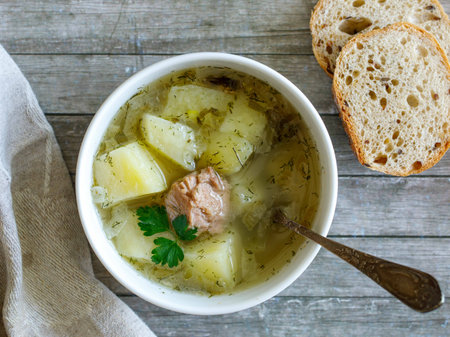 Simple and tasty Canned fish soup with potato and rice in a bowl on wooden background. Close up, top view from above.の写真素材