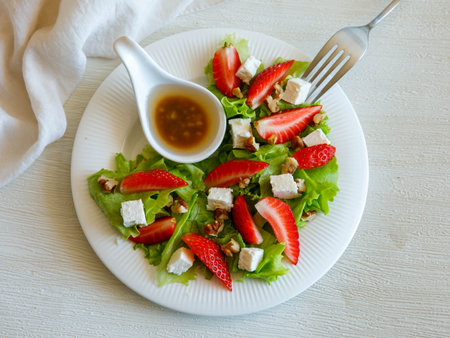 Plate of homemade fresh summer sliced Strawberry and lettuce salad with feta cheese and walnuts. Organic healthy diet, vegetarian salad food. top view.の写真素材