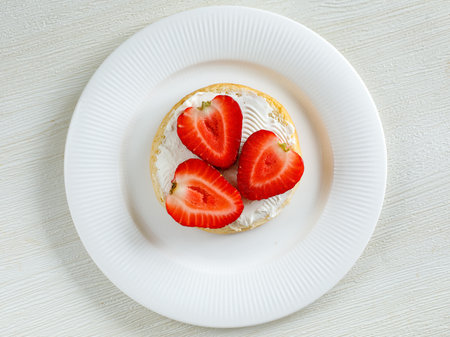 Top view of tasty bruschetta with cream cheese and ripe strawberries on white plate on white background.の写真素材