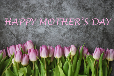 Happy mother's day inscription with frame made from pink purple fresh tulips on dark marble background. Top view flat lay, copy space. greeting cardの写真素材