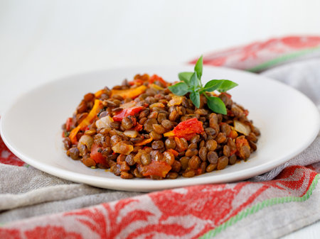 White plate of delicious vegetarian homemade gren lentil with tomatoes, carrot and onion on kitchen towel. healthy lifestyle. Diet menu. side viewの写真素材