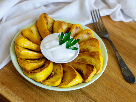 Fried patisson or yellow zucchini with sour cream garlic sauce and greens, on wooden background.の写真素材