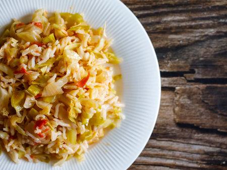 Traditional homemade Mediterranean Crete cuisine rice with vegetables cabbage, onion and tomato on white plate on old wooden table. Vegetarian healthy lunch or dinner idea. top viewの写真素材