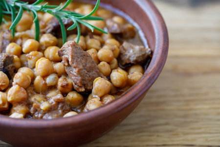 Traditional homemade delicious Crete food Chickpeas with Meat and tomato onion sauce in clay bowl on wooden table background. Horizontal, side view, close up, copy spaceの写真素材