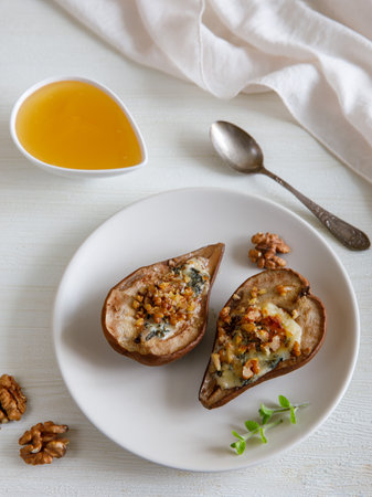 Homemade baked pears with blue cheese, nuts and honey on a plate. french cuisine. Keto diet. Vegetarian lunch. top view, vertical.の写真素材