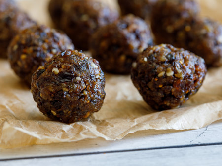 Healthy organic homemade delicious energy balls: chocolate balls cakes made from raisin, prune, dates, walnut, figs on baking paper against white background. close up macroの写真素材