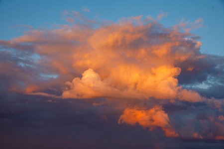 Large fluffy white and orange pink clouds in the sunset light. Evening dawn or sunset sky beautiful background, horizontalの写真素材