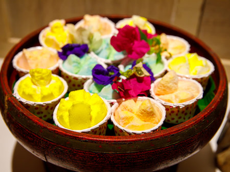 Three pieces of colorful Thai style cup cake bakery, Thai Rice Flour Muffin or known as Khanom Tuay Foo in pastel soft color tone with flowers in clay plateの写真素材