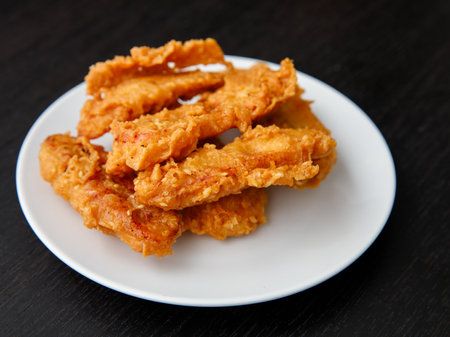 deep-fried fritters sliced banana, also known as Kluay khek, served on white plate on black wooden table.の写真素材