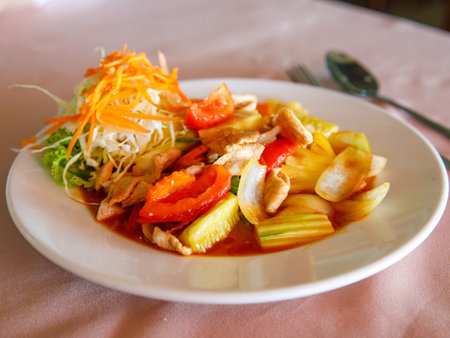Sweet and sour stir fried pork, thai traditional food with pineapple, cucumber, tomato and other vegetableの写真素材