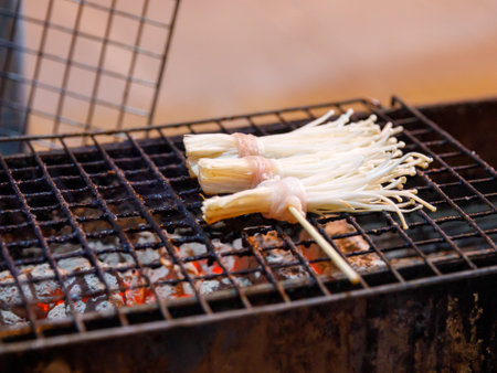 Bacon roll with Golden Needle Mushroom, Thailand Phuket street stall BBQ sticks. Enokitake Mushroom wrapped bacon, on skewers barbecue grilled in night market local street food.の写真素材