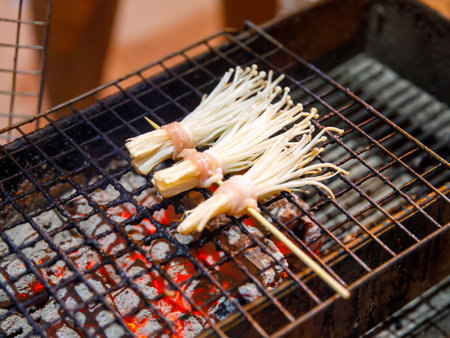 Bacon roll with Golden Needle Mushroom, Thailand Phuket street stall BBQ sticks. Enokitake Mushroom wrapped bacon, on skewers barbecue grilled in night market local street food.の写真素材