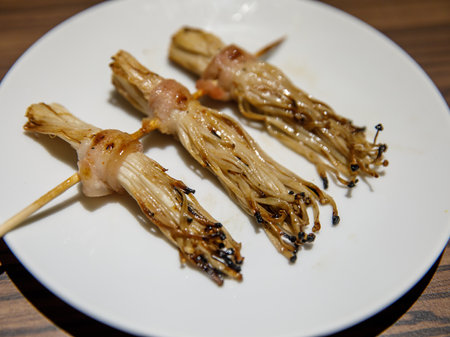 Bacon roll with Golden Needle Mushroom, Thailand Phuket street stall BBQ sticks. Enokitake Mushroom wrapped bacon, on skewers barbecue grilled in night market local street food.の写真素材