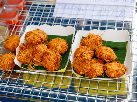 Deep Fried Pork Balls Wrap in rice Egg Noodles (Moo Sa Rong or Sarong) lying on banana leaves and paper plate on street food market tray, Thai Traditional fast Food, close up, top viewの写真素材