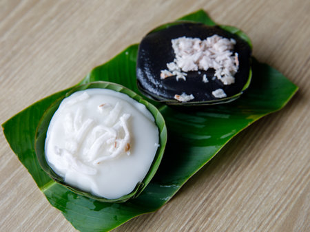 Thai Desserts Mung Bean Flour in Jelly topping with coconut milk Khanom Leum Kleun or Gleun. And Black Grass jelly Chao Kuai. Colorful Thailand desserts in banana leaves cupの写真素材