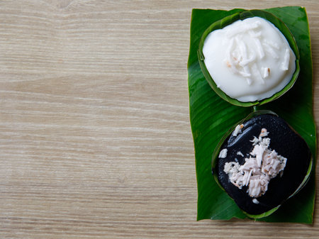 Thai Desserts Mung Bean Flour in Jelly topping with coconut milk Khanom Leum Kleun or Gleun. And Black Grass jelly Chao Kuai. Colorful Thailand desserts in banana leaves cup, top view, copy spaceの写真素材
