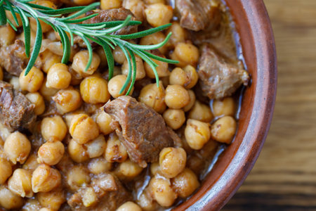 Traditional homemade delicious Crete food Chickpeas with Meat and tomato onion sauce in clay bowl on wooden table background. horizontal, top view, close upの写真素材