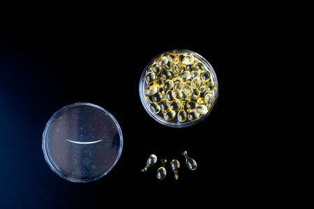 soft gel cosmetic capsule that could be used for anything from omega 3, flax seed oil, fish oil, vitamin d, or vitamin e. Caring for the health of the skin and body. On black background. Copy spaceの写真素材