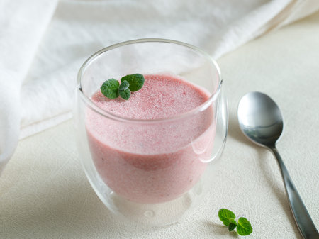Healthy Strawberry Cream mousse in glass on a white wooden table with mint leaves and spoon. Delicious summer dessert.の写真素材