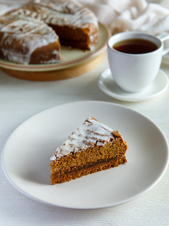 piece of Pryanik, Krasnoarmeysk, traditional ethnic Russian sweet gingerbread made with honey, spices and apple jam, from city of Saratov, covered with sugar icing. On plate with cup of tea. Verticalの写真素材