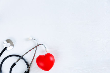 Stethoscope and red heart on white wooden background. Health care concept. Top view, copy spaceの写真素材