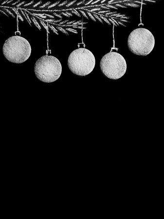 Drawing fir tree branch and Christmas gingerbread cookies like new year balls hanging on black chalk board background. Merry christmas and happy new year, bw border with copy space, top view vertical.の写真素材