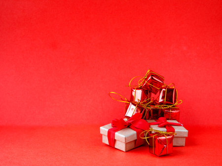 Christmas gift boxes wrapped in red paper on red background. Side view copy space, minimalism, monochromeの写真素材