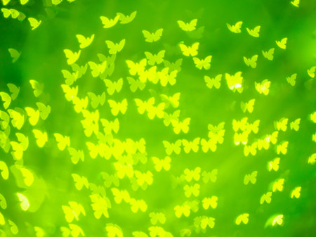 abstract yellow butterfly shape bokeh on green blurred light background. Hello summer or spring conceptの写真素材