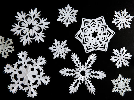 Set of snowflakes cut out of white paper on a black background. Handmade new year and Christmas decorationの写真素材