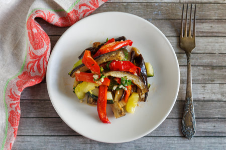 Baked vegetables in sweet and sour sauce on plate. Eggplant, zucchini, paprika and garlic. Healthy vegetarian food, top viewの写真素材