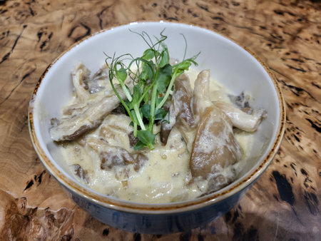 Bowl with delicious oyster mushrooms with creamy sauce on wooden background, close up, with microgreens.の写真素材