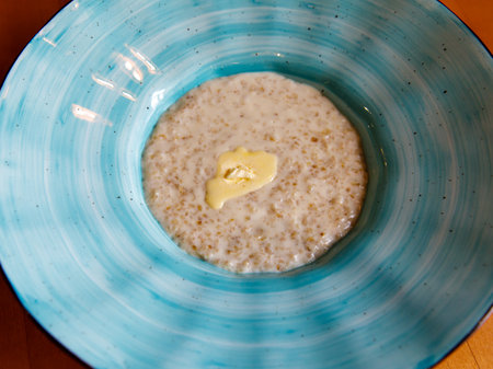 Healthy breakfast oatmeal porridge in blue bowl on wooden table. Warm porridge oats, vegan vegetarian weight loss dieting breakfast food. Close up.の写真素材
