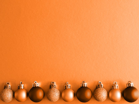 Christmas tree toys border on apricot crush trend 2024 color background. Christmas decorations on a shiny surface. Balls and garland of orange and brown colors on table. Top view flat lay. copy space.の写真素材