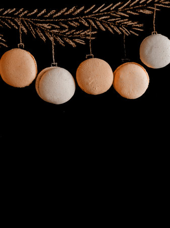 Drawing fir tree branch and Christmas macarons like new year balls hanging on apricot crush trend 2023 color background. Merry christmas and happy new year, border with copy space, top view. Vertical.の写真素材