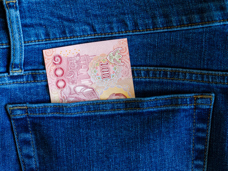 Close up banknote 100 thai bath in blue jeans back pocket top view with copy space.. concept saving, investment, stock market and transfer money. Exchange Rates.の写真素材