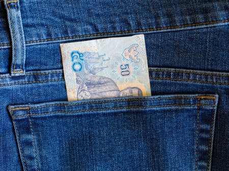 Close up banknote 50 thai bath in blue jeans back pocket top view with copy space. Budget travel or shopping, low earnings, economical crisis, pocket money concept. Exchange Rates.の写真素材