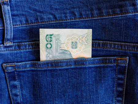 Close up one banknote 20 thai bath in blue jeans back pocket top view with copy space. Budget travel or shopping, low earnings, economical crisis, pocket money concept. Exchange Rates.の写真素材