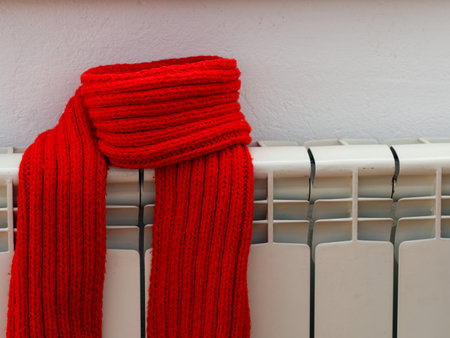 Energy efficiency concept. Wrapped scarf on heating radiator battery indoors.の写真素材