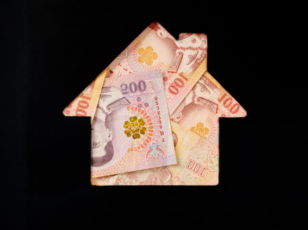 Thai bath banknote in shape of house on black background. Concept of Investment property, mortgage, Investment risk and uncertainty in real estate housing market, utility bills. Top view flat lay.の写真素材