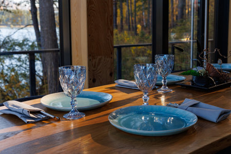 Preparing for party in forest luxury restaurant on river bank. Decorated served table await guests. Decoration Details. large window with wild mountain forest view. Tourism and vacationsの写真素材