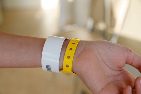 close-up of yellow plastic bracelet on the girl arm of child clinic patient, check tape with entry number on hand of teenager girl, event ticket concept.の写真素材