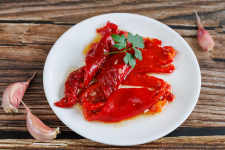 Peeled peppers, salad from grill baked marinated vegetable pepper, grilled fresh, portion on plate, ready to eat meal snack on the table, top view, food background, rusticの写真素材