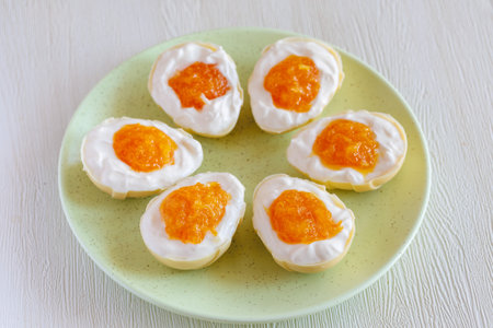 Gourmet homemade white chocolate half easter egg, stuffed with cream cheese and orange jam looks like whites and yolk. Easter egg with pudding cream, Easter dessert. Easter conceptの写真素材