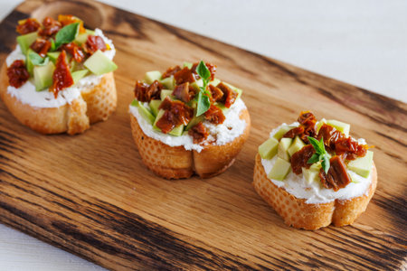 selective focus of italian bruschetta with dried tomatoes, avocado, cream cheese and herbsの写真素材