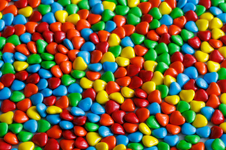 Colorful sweet little glazed multicolored chocolate bonbons candies, m and ms with heart shapes, full frame background, close upの写真素材