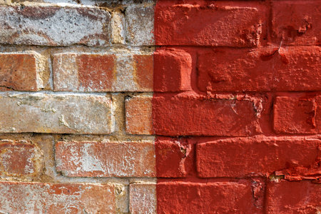 Old urban weathered brick wall half painted with red paint, two different parts . Bicolor abstract background, close upの写真素材