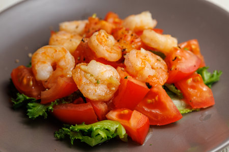 Fresh summer salad with shrimp, tomato and lettuce on grey plate close up. Concept of healthy eatingの写真素材