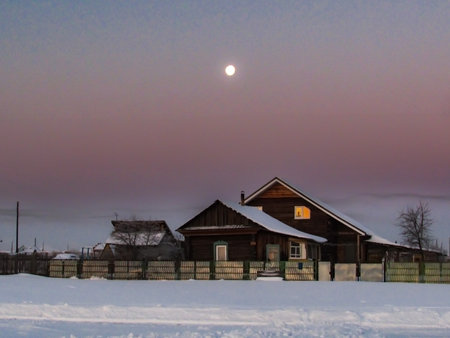 Fantastic winter landscape with wooden house in snowy village in foggy sunset sky. Christmas and winter vacations holiday conceptの写真素材