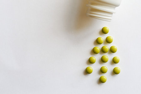Round green tablet in shape of Christmas tree from bottle spill out isolated on white background. Unusual creative tree. Christmas and New Year medical concept. Copy spaceの写真素材